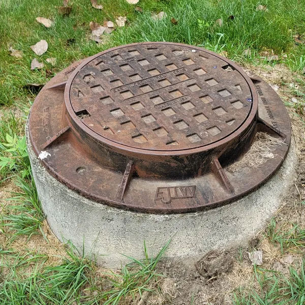 Raised sewer manhole cover installed in concrete collar