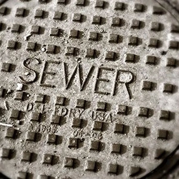 Close-up of metal sewer manhole cover with raised lettering