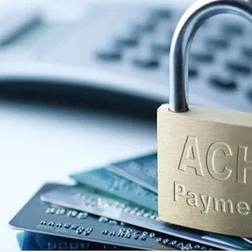 Padlock labeled ACH payment resting on credit cards, representing secure electronic bank payments.