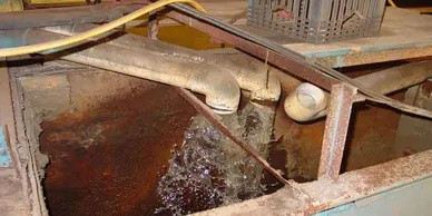 Open industrial grease trap containing wastewater and grease buildup.