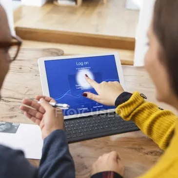 Two people reviewing a laptop screen showing an online login and payment process.